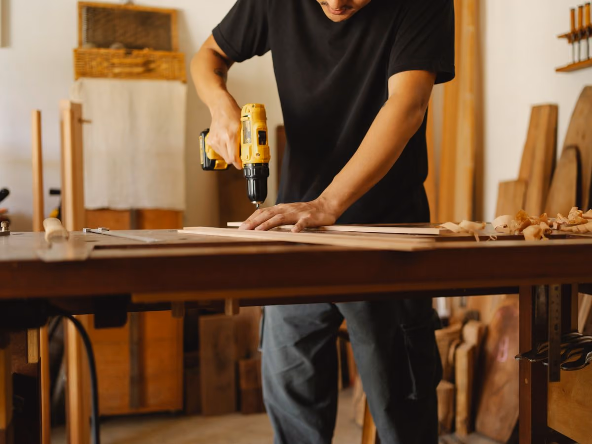 Carpenter drilling a wooden plank in the workshop